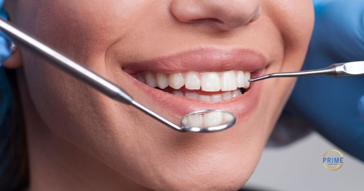 Close-up de sorriso feminino com dentes brancos sendo examinado com espelho e sonda odontológica, com logo da Prime Saúde Oral