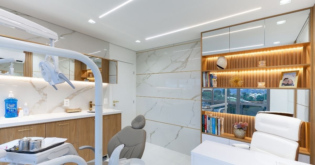 Interior do consultório odontológico da Prime Saúde Oral em Alphaville com cadeira odontológica, revestimento em mármore branco, marcenaria em madeira e iluminação sofisticada