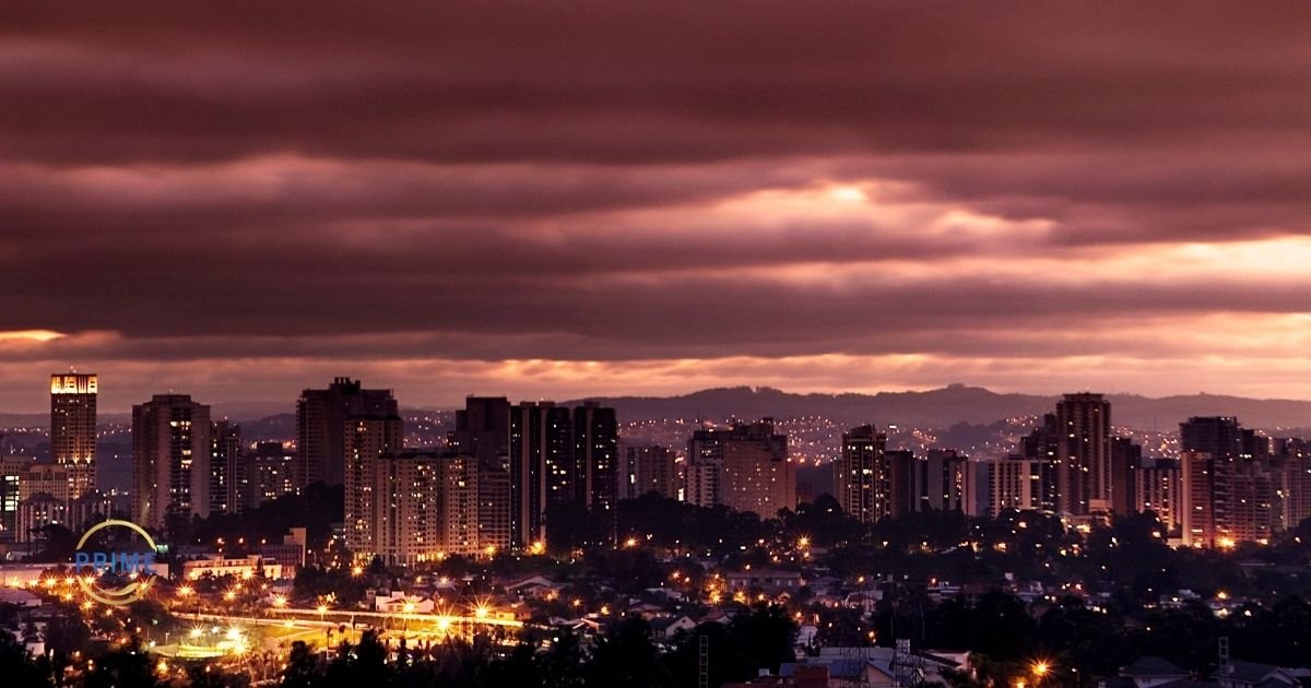 Vista panorâmica noturna da cidade de Barueri com prédios iluminados, luzes das ruas e céu dramático ao entardecer, com logo da Prime Saúde Oral