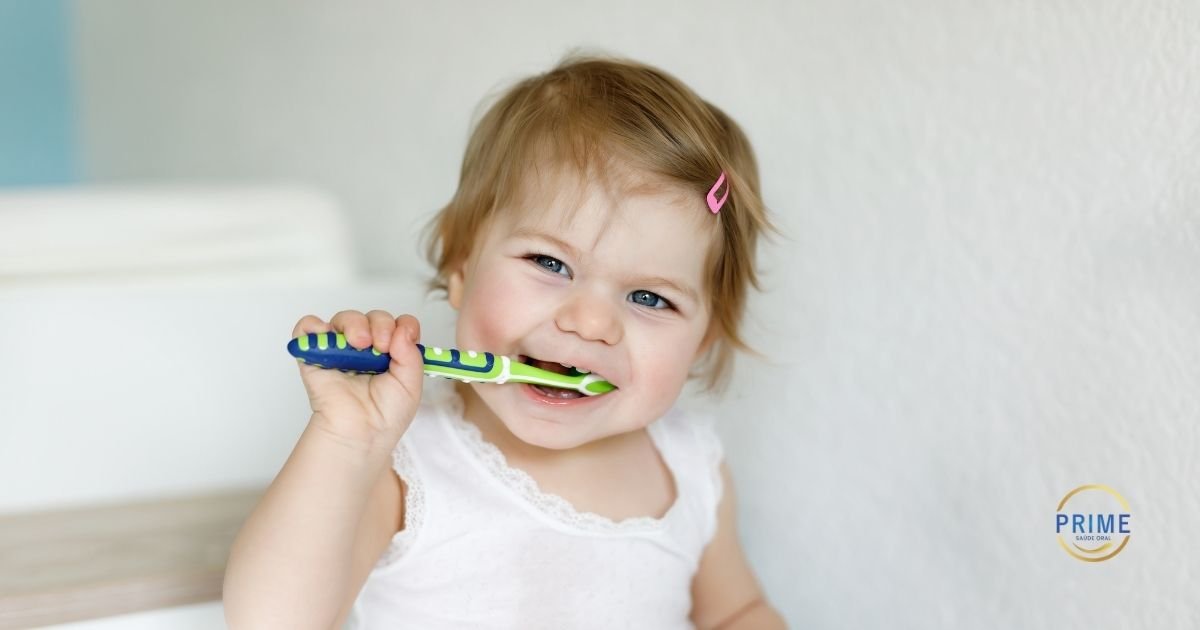 Bebê sorrindo enquanto segura escova de dentes infantil