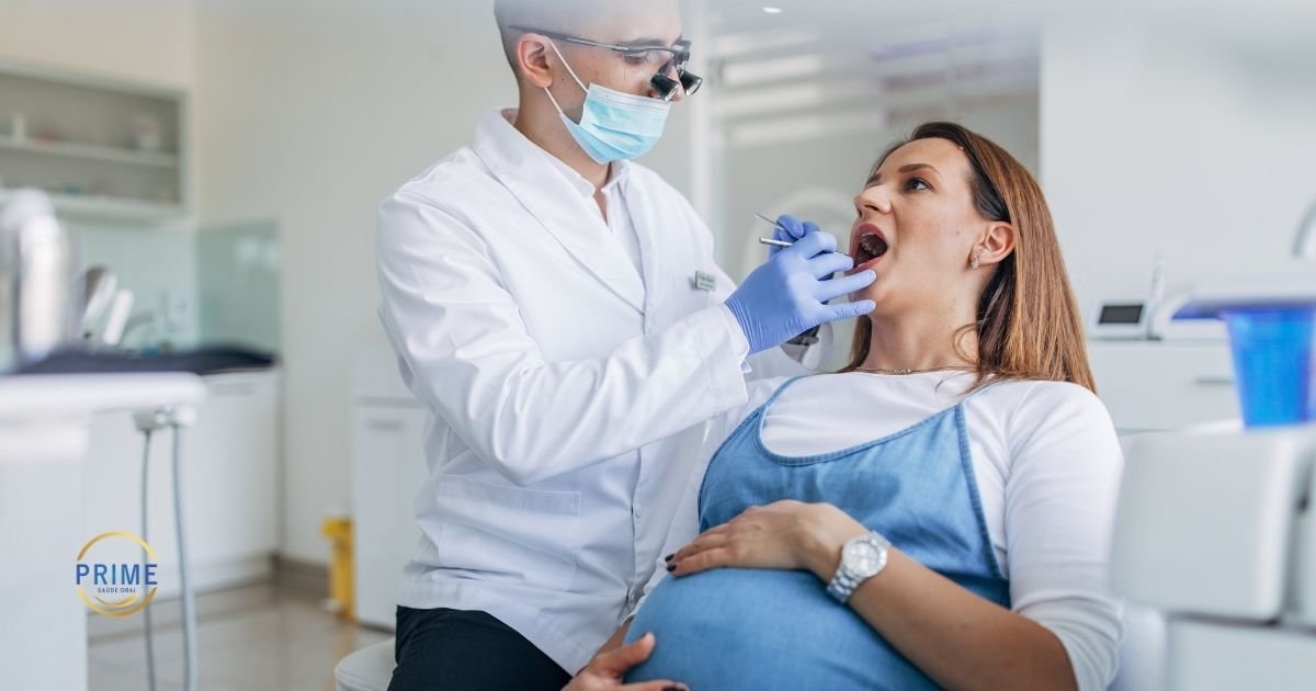 Gestante com barriga avançada sendo examinada por dentista com máscara, luvas e jaleco branco em consultório odontológico moderno, com logo da Prime Saúde Oral
