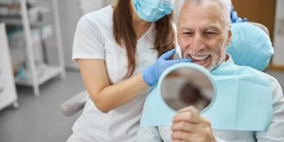 Modelo de implante dental com coroa protética sobre superfície clara